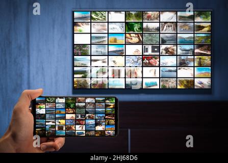 Diffusion de télévision, diffusion de télévision. Un homme avec un téléphone dans sa main et un téléviseur avec la même image sur les écrans. Cross-plate-forme.Vidéo à la demande en streaming multimédia c Banque D'Images