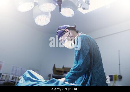Avec précaution.Photo d'un jeune chirurgien spécialisé effectuant une chirurgie sur un patient dans une salle d'opération. Banque D'Images