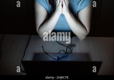 une femme fait des heures supplémentaires.Un étudiant étudiant étudiant étudiant à un ordinateur portable la nuit dans l'obscurité.La jeune fille s'inquiète des problèmes au travail et tient ses mains sur son visage. Banque D'Images