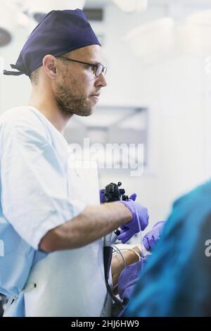Sauver des vies est ce qu'il fait.Cliché d'un jeune chirurgien effectuant une chirurgie sur un patient dans une salle d'opération. Banque D'Images