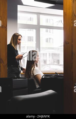 Maître femme coiffeur boucle doucement cheveux curling fille dans un salon de beauté. Coiffage Banque D'Images