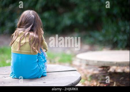 Tilburg, pays-Bas.Jeune écolière assise enfoncée dans une cour de jeu parce qu'elle n'est pas en mesure de rencontrer ses amis avec qui jouer à cause de Corna.NOTE: Illustration image faite en 2013 avant Corona! Banque D'Images