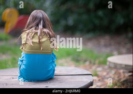 Tilburg, pays-Bas.Jeune écolière assise enfoncée dans une cour de jeu parce qu'elle n'est pas en mesure de rencontrer ses amis avec qui jouer à cause de Corna.NOTE: Illustration image faite en 2013 avant Corona! Banque D'Images