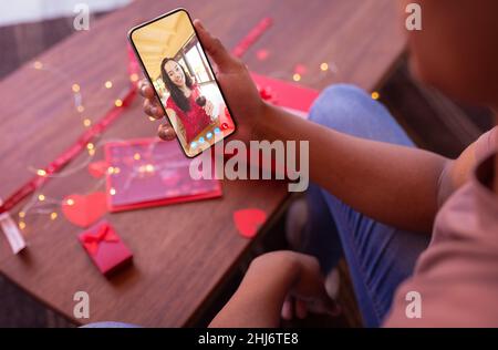 Jeune femme biracial avec du vin lors de rencontres en ligne avec le petit ami afro-américain le jour de la Saint-Valentin. Non modifié, rencontres en ligne, appel vidéo, vitiligo a Banque D'Images