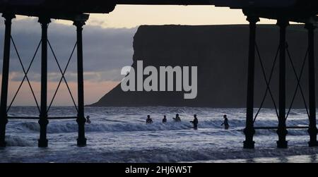 Les nageurs s'attaquent aux vagues de la mer du Nord à Saltburn, dans le Yorkshire du Nord.Date de la photo: Jeudi 27 janvier 2022. Banque D'Images