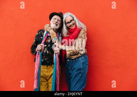 Joyeux couple senior souriant tout en se tenant debout sur un fond rouge.Couple insouciant portant des vêtements décontractés colorés.Joyeux matu Banque D'Images