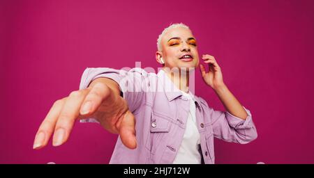 Homme non-conformant de sexe appréciant sa chanson préférée.Un homme de queer qui ne se conforme pas danse tout en écoutant de la musique sur des écouteurs sans fil.Jeune homme stan Banque D'Images