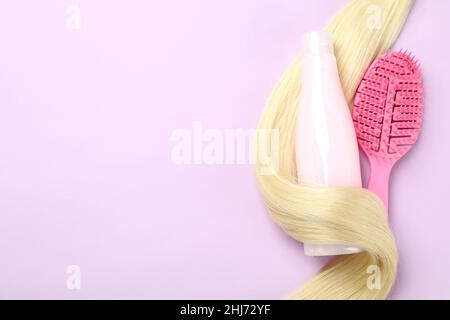 Mèche de cheveux, shampooing et brosse à cheveux sur fond violet Banque D'Images