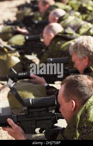 Visée basse.Une ligne de soldats mentant et visant avec leurs armes. Banque D'Images