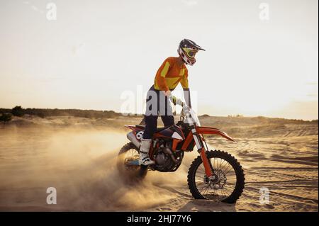 Pilote de motocross sur le moteur de sport au-dessus de la poussière paysage Banque D'Images