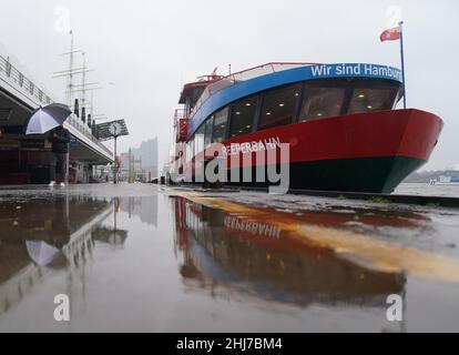 Hambourg, Allemagne.27th janvier 2022.Un homme avec un parapluie marche sous la pluie à travers les étapes de l'atterrissage dans le port de Hambourg.Credit: Marcus Brandt/dpa/Alay Live News Banque D'Images