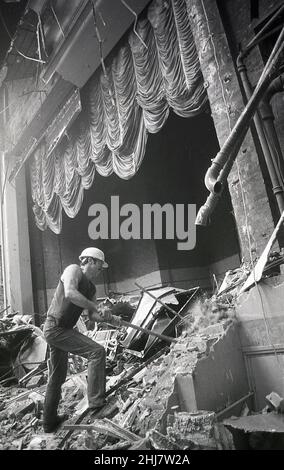 1987, historique, un homme travaillant dans un casque et en utilisant un marteau en traîneau démolissant la zone de scène de l'ancien cinéma ABC à York, Angleterre, Royaume-Uni.Le rideau lourd qui était descendu à la fin du film reste in situ pendant que le travailleur frappe la structure.En 1937, la Regal a été rebaptisé « ABC » (Associated British Cinemas) Cinema en 1961.Il est devenu un cinéma à trois écrans en 1980, mais l'époque changeante pour les grands écrans l'a vu fermé pour de bon en 1986, avant que l'ensemble du bâtiment ne soit terminé démoli en 1989. Banque D'Images