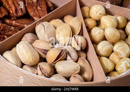 boîte en bois avec des cellules pour différents fruits à coque nourriture pour la nutrition des protéines saines pistache gros plan, personne. Banque D'Images