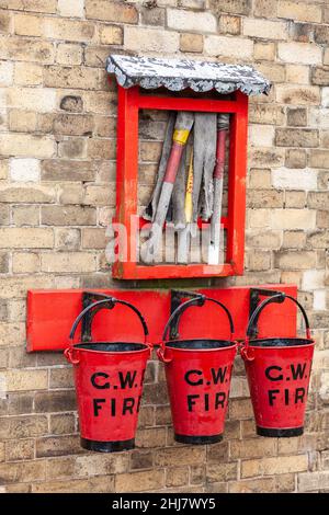 Seaux d'incendie GWR rouge vif et équipement de lutte contre les incendies sur le vieux mur de brique Banque D'Images