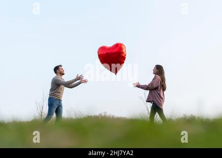 Jeune couple célébrant le jour de la Saint-Valentin jouant avec un ballon en forme de cœur Banque D'Images