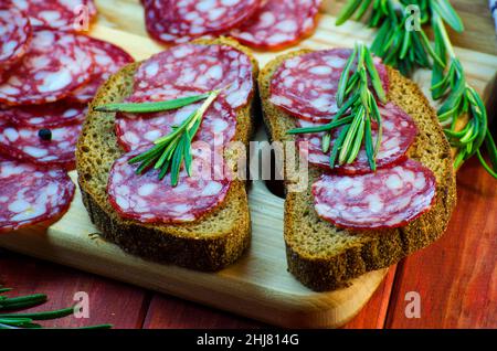 sandwichs à la saucisse sur un panneau en bois et épices en gros plan Banque D'Images