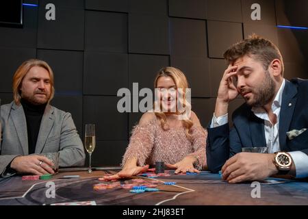 Une femme qui réussit à racler des jetons tout en gagnant un jeu de poker Banque D'Images