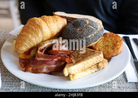 Délicieux petit déjeuner en Suisse. Assiette de différents produits de boulangerie comme le pain et le croissant, omelettes, viandes et plus encore. Gros plan sur l'image couleur. Banque D'Images