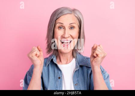 Photo d'une dame aînée étonnée mains poings porter blazer bleu isolé sur fond rose pastel Banque D'Images