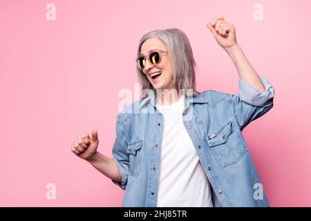 Photo de femme aînée sportive danse look vide espace port lunettes bleu blazer isolé sur fond de couleur rose Banque D'Images