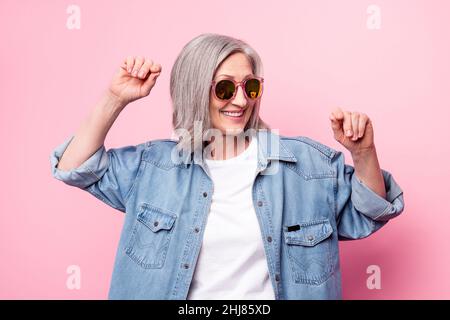 Photo de fantaisie femme aînée look vide espace port lunettes blouson bleu isolé sur fond rose pastel Banque D'Images