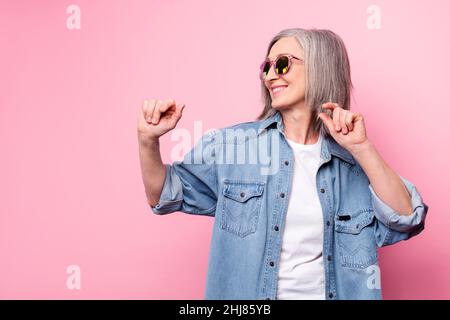 Photo d'une femme fraîche et âgée danse look vide espace porter lunettes chemise bleue isolée sur fond rose pastel Banque D'Images