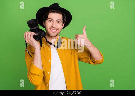 Portrait de jeune caméraman positif de bonne humeur montrant le pouce vers le haut comme un feedback isolé sur fond vert Banque D'Images