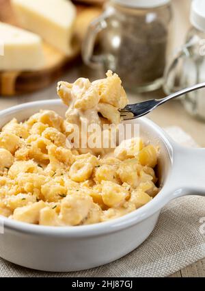 Macaroni au fromage sur une fourchette et dans un plat blanc sur une table en bois Banque D'Images