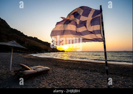 Drapeau grec agitant au coucher du soleil sur une plage de sable en Crète, Grèce.Vue idyllique du drapeau grec sur la belle plage de Sfinari en Crète, Grèce. Banque D'Images