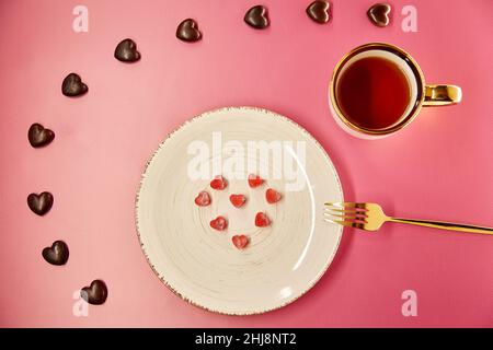 Mignons coeurs glacés sur plaque blanche avec fourchette.Bonbons au chocolat.Dîner romantique créatif, concept de la Saint-Valentin.Arrière-plan dégradé rose.Vue de dessus. Banque D'Images