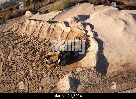 Chargeur frontal pendant les opérations de creusement et d'excavation dans une fosse ouverte.La chargeuse sur pneus charge le sable dans la carrière.Gravier concassé pour l'industrie de la construction. Banque D'Images