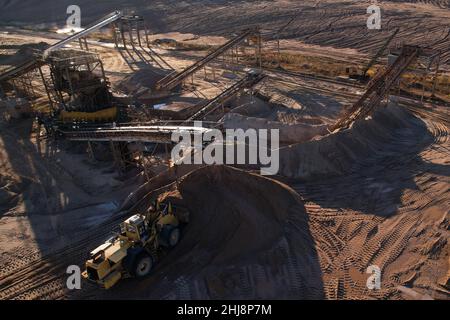 Le chargeur sur roues décharge le sable pour l'écraser en fractions dans l'usine de broyage.Production de sable de construction près de la carrière.Vue aérienne d'une exploitation minière Banque D'Images