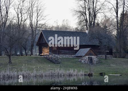 Ancienne maison en bois au bord de la forêt près du lac au printemps.Village de pêcheurs.Extérieur traditionnel de style soviétique ou russe Banque D'Images