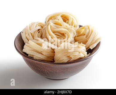 Pâtes tagliatelles non cuites dans un bol en céramique isolé sur fond blanc avec passe-cheveux Banque D'Images