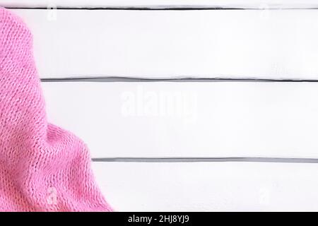Tissu tricoté rose chaud sur table en bois blanc avec espace pour copier.Flat lay, vue de dessus Banque D'Images