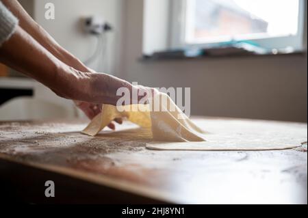 Vue à angle bas d'une femme qui fait de la pâte à strudel maison sur une table à manger à la farine saupoudrée. Banque D'Images