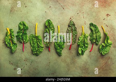 Le verger suisse arc-en-ciel laisse sur fond rouillé, légumes feuilles verts crus, vue du dessus, espace copie Banque D'Images