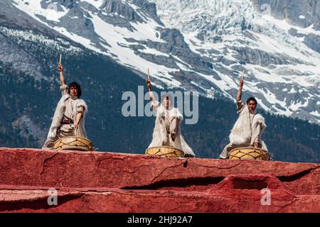 La minorité ethnique du peuple Naxi dans ses costumes traditionnels ; scène d'une représentation avec la montagne enneigée du Dragon de Jade en arrière-plan Banque D'Images