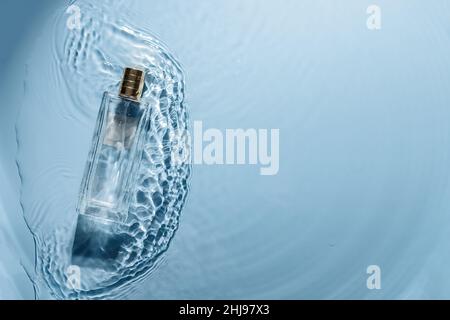 Flacon de parfum sur fond bleu ondulé.Concept de parfum de la mer fraîche.L'essence des femmes et des hommes Banque D'Images