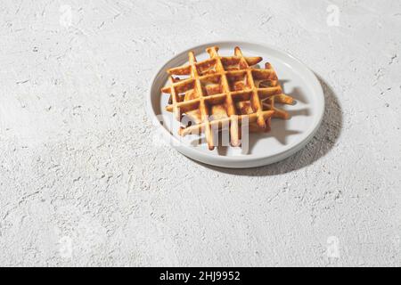 Gaufres belges fraîchement cuites sur une assiette blanche sur une table légère, espace copie Banque D'Images