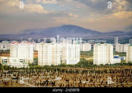 Paysage urbain, gratte-ciel avec des bâtiments en marbre et de nouveaux parcs à Ashgabat, la capitale du Turkménistan en Asie centrale.Lumière dorée au coucher du soleil. Banque D'Images