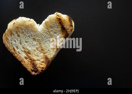 tranche de pain grillé en forme de cœur, macro de pain grillé isolé sur le noir, avec beaucoup d'espace de copie.Concept de l'amour de la nourriture Banque D'Images