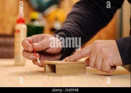 Les mains de menuisier encollent le bois de gros plan Banque D'Images