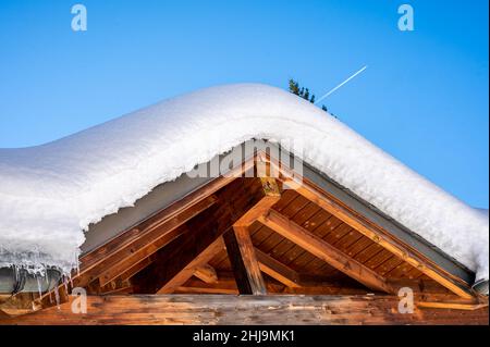 Toit recouvert de neige avec ciel bleu.Bâtiment en bois en hiver. Banque D'Images