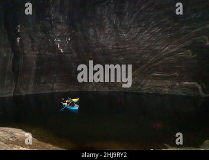 Turda, Roumanie-24 août 2021: Photo de l'intérieur de la mine de sel de Turda, dans laquelle les gens peuvent être vus dans les bateaux sur le lac entouré par des murs de sel Banque D'Images