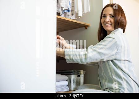 La fille choisit ses vêtements dans le placard. Une garde-robe bien organisée. Articles empilés verticalement dans des paniers. Rangement des vêtements. Banque D'Images