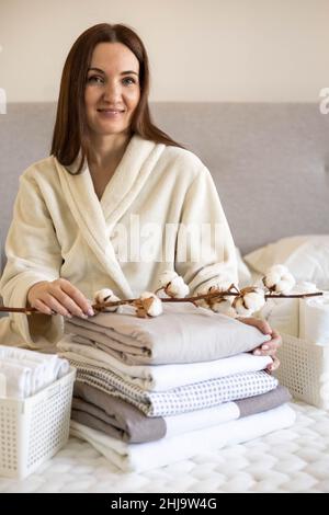 Les mains de la femme bien entretenues tiennent la branche de coton avec la pile de draps pliés et de couvertures Banque D'Images