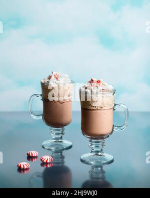 Café moka à la menthe poivrée d'hiver photographié dans un studio avec toile de fond nuageuse et reflet de verre Banque D'Images