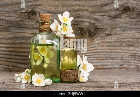 Huile de massage aux herbes et fleurs de jasmin fraîches sur fond de bois rustique Banque D'Images