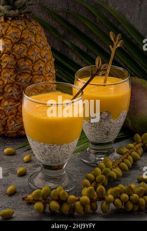 La photo montre un dessert végétalien en verre.Les aliments sains ont deux couches: Le fond est blanc avec des graines de chia faites de yaourt et le dessus est jaune, Banque D'Images